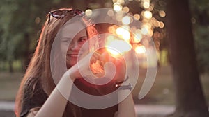 Beautiful woman making heart shape with hands at sunset