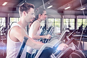 Beautiful woman and man exercising on elliptical machine