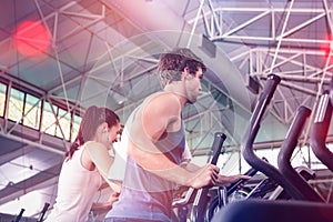 Beautiful woman and man exercising on elliptical machine