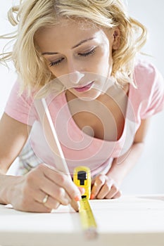 Beautiful woman marking table with measure tape