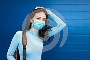 Beautiful woman with a medical mask on her face with a backpack on her back on
