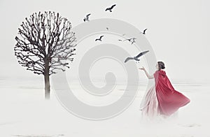 Beautiful woman in medieval dress with birds on foggy field