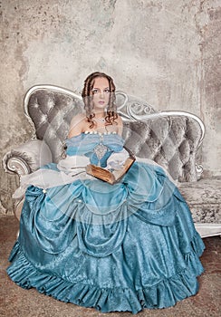 Beautiful woman in medieval dress with book on the sofa