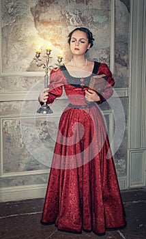 Beautiful woman in medieval dress with candelabrum