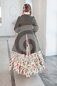 Beautiful woman in medieval dress and frock-coat. Back pose