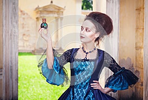 Beautiful woman in medieval dress with perfume bottle