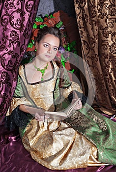 Beautiful woman in medieval dress reading book