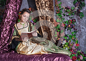 Beautiful woman in medieval dress reading book