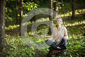 Beautiful woman meditating in the forest on a sunny morning