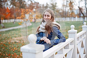 Beautiful woman model poses outdoor in the autumn park with knitten gray scarf