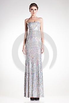Beautiful woman model posing in long elegant silver sequins dress