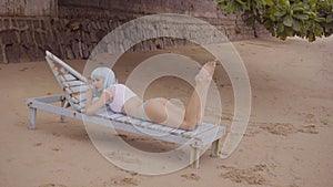 beautiful woman in modern futuristic style posing on the damaged wooden blue sunbed