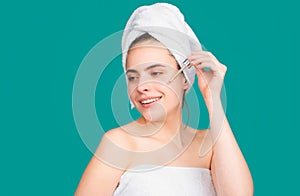 Beautiful woman moisturizing face with oil. Beauty face of a cheerful attractive girl with towel on head, isolated