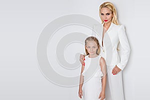 Beautiful woman mother with daughter snuggling together and show love, smartly dressed in a white dress
