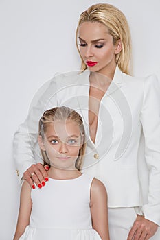 Beautiful woman mother with daughter snuggling together and show love, smartly dressed in a white dress