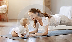 Beautiful woman mother practicing yoga with baby kid at home