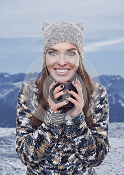 Beautiful woman with mug in ski resort, winter season