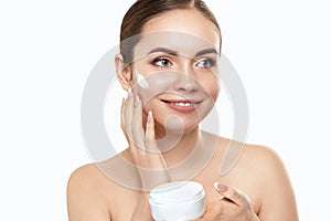 Beautiful woman with nature makeup smiling. Beauty portrait of female face holding and applying cosmetic cream. Skin care.