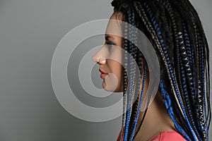 Beautiful woman with nose piercing and dreadlocks on grey background. Space for text