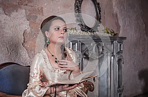 Beautiful woman in old historic medieval dress with book