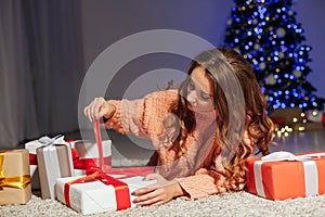 Beautiful woman opens gifts at the Christmas tree for the new year lights garland