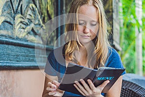 Beautiful woman ordering from menu in restaurant and deciding what to eat