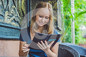 Beautiful woman ordering from menu in restaurant and deciding what to eat