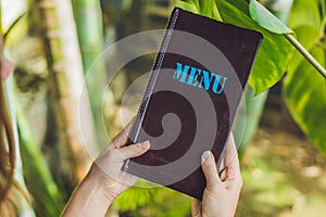 Beautiful woman ordering from menu in restaurant and deciding what to eat