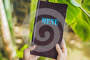 Beautiful woman ordering from menu in restaurant and deciding what to eat