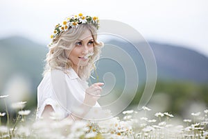 Beautiful woman outdoors with a bouquet of white daisies on a blooming mountain meadow
