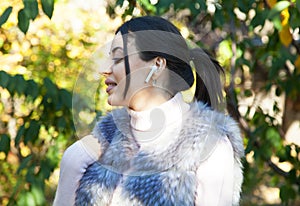 Beautiful woman outdoors, has a wireless earphones in her ears