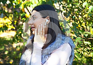 Beautiful woman outdoors, has a wireless earphones in her ears