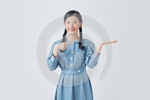 Beautiful woman over white background , showing and pointing something that is on her hand surprised