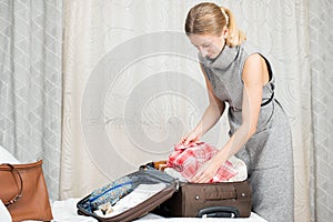 Beautiful woman packing suitcase in bedroom getting ready for road trip