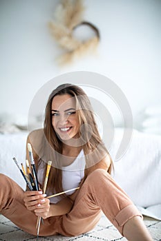 Beautiful woman painter with a brushes at home