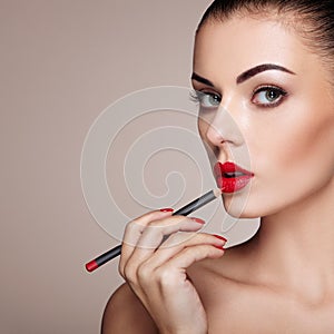 Beautiful woman paints lips with lipstick