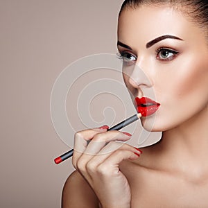 Beautiful woman paints lips with lipstick