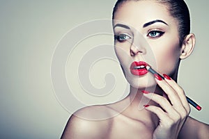 Beautiful woman paints lips with lipstick