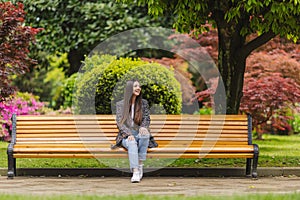 beautiful woman in the park sitting on the bench. Modern urban recreation