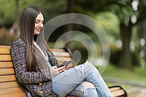 beautiful woman in the park sitting on the bench. Modern urban recreation