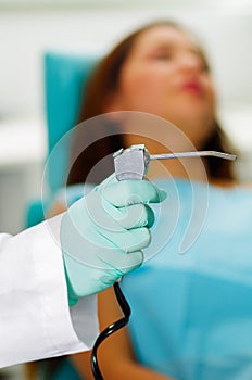 Beautiful woman patient having dental treatment at dentist`s office while the doctor is holding an instrument