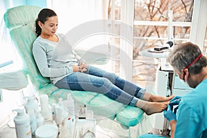 Beautiful woman patient on pedicure treatment with pediatrician chiropodist