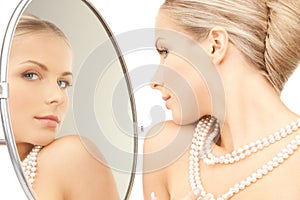 Beautiful woman with pearl beads and mirror