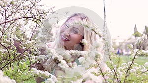 Beautiful woman peeps from behind a flowering bush.