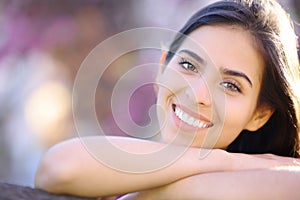 Beautiful woman with perfect teeth smiling at you in a park