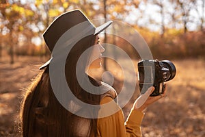 beautiful woman photographer taking photos in autumn forest using SLR camera