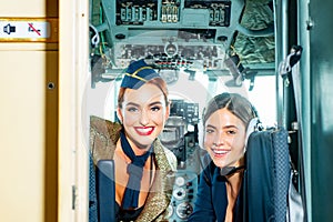 Beautiful woman pilot wearing uniform. Happy and successful flight. Looking at camera in plane. Girls looking at camera