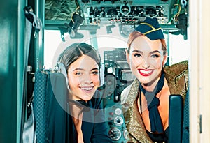 Beautiful woman pilot wearing uniform. Happy and successful flight. Looking at camera in plane. Girls looking at camera