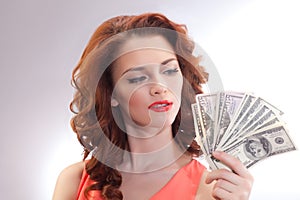 A beautiful woman in a pink dress with dollar banknotes in the hands