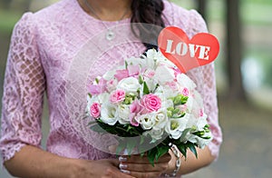 Beautiful woman in pink dress holding a wedding bouquet of flowers, summer time, love, Valentine`s day